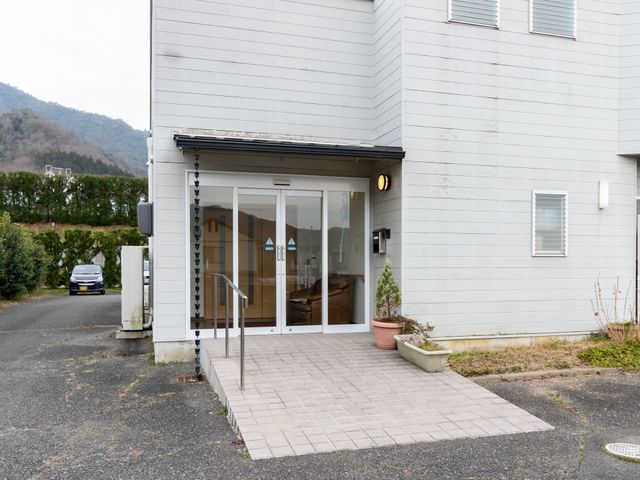 白壁の建物のエントランス 外観 開けやすい自動ドアの入口は、通風良く清潔感のあるアプローチが魅力です。ここから新たな職場への一歩を踏み出しましょう。