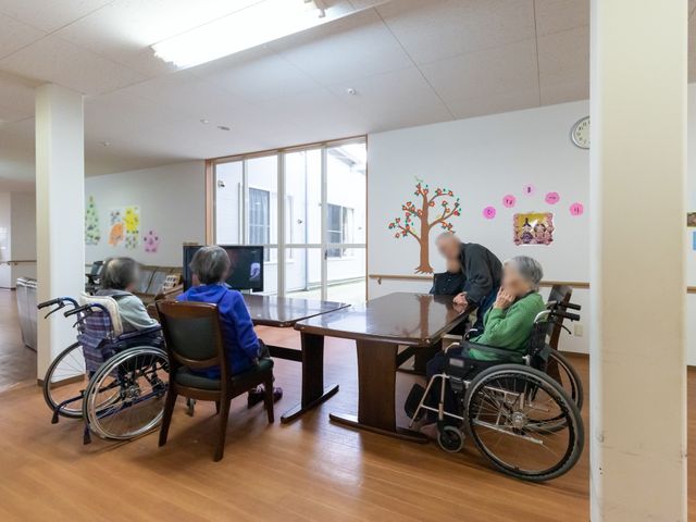 車椅子の方々と共有スペース 共有スペース ゆったりとした共有スペースで、来訪者の方々が憩いのひとときを過ごしています。壁に飾られたアートは温かい雰囲気を醸し出しています。