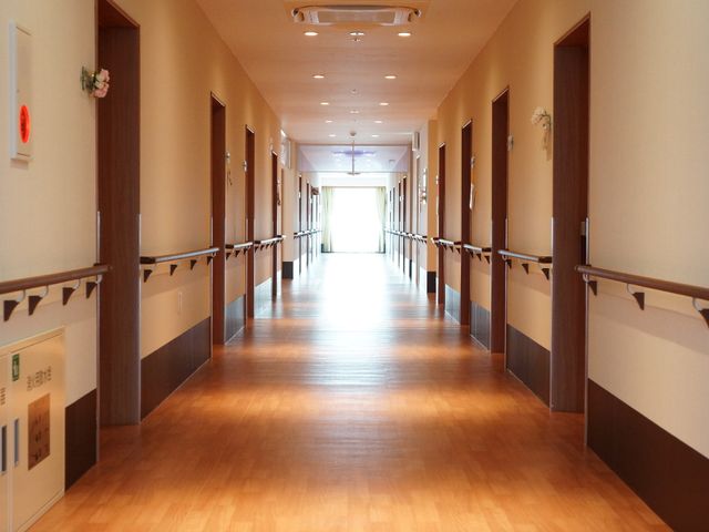 明るい廊下の風景 廊下 床が木目調で、手すりが両側に備わった廊下です。安心して歩行ができる環境が整っております。