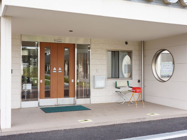 明るいエントランスエリア 入口 広々としたエントランスは安心のバリアフリー設計です。椅子が置かれ、待合せや一息つく場所としてもご利用いただける環境を整えています。