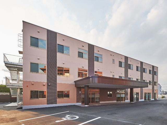 清潔感のある建物のエクステリア 外観 開放感のあるエントランスが迎える、落ち着いた色合いの建物です。就業するには、心地よい職場環境が整っています。
