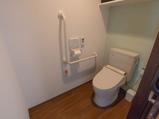 手すり付きトイレ設備 トイレ 安全に配慮されたトイレは、手すりや操作パネルが備え付けられ、使いやすさを追求しています。
