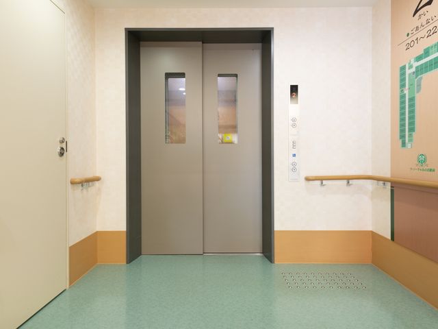 エレベーターホールの様子 エレベーター 手すりが設けられ、足元には視覚障がい者用の案内ブロックがあるため、すべての方が使いやすい配慮が施された移動スペースです。