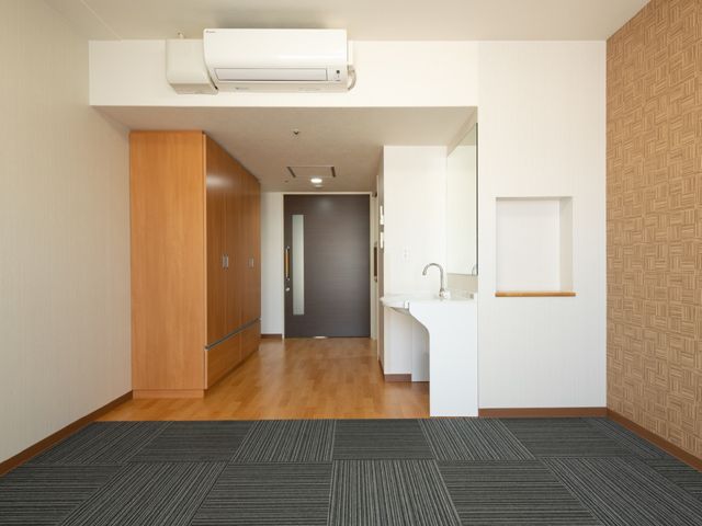 清潔な室内の一角 居室 温もりを感じる木目調の家具と、シンプルな構造の居室が組み合わさり、心地よい空間を創出しております。掃除が行き届いており、快適にお過ごしいただける環境です。