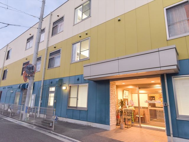 カラフル外観の建物エントランス 外観 明るくカラフルなエントランスには居心地の良さを感じさせる植物とチェアが配置されています。訪れる人々への心遣いが感じられる空間です。