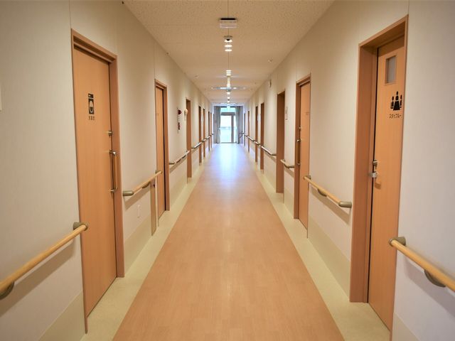廊下の明るい風景 廊下 手すりの設置された温かみのある色彩の廊下です。壁は明るく、清潔感がありますので、快適な移動が可能です。