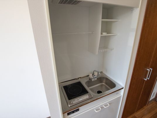 クローゼットに隣接して、ミニキッチンが設置されている。電気式コンロや収納棚、換気扇なども備えられている。
