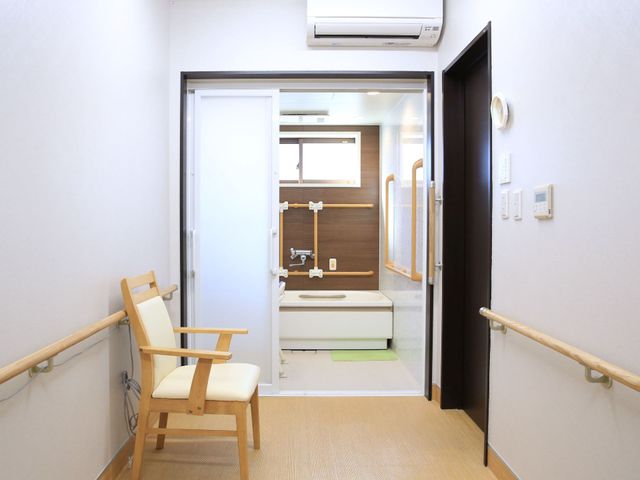 バリアフリー浴室入口 脱衣所 手すりが設けられた清潔感のある浴室入口で、安心してご入浴いただけます。明るく広々とした設計は、日々の暮らしをサポートします。