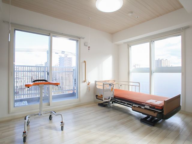 居室のベッドと窓 居室 ゆったりとした居室には、天井の高さと光が差し込む窓があり、開放感のあふれる空間で快適に過ごせます。