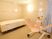 床と壁にタイルが貼られた浴室内に介護浴槽がある。壁に大きな丸い電球色の照明が設置され、水色のカーテンが掛けられている。