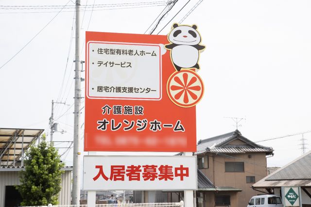 オレンジ色の施設看板 看板 目を引くオレンジ色の看板は、来訪者を温かくお迎えします。癒しのイラストが印象的で親しみやすい空間を予感させます。