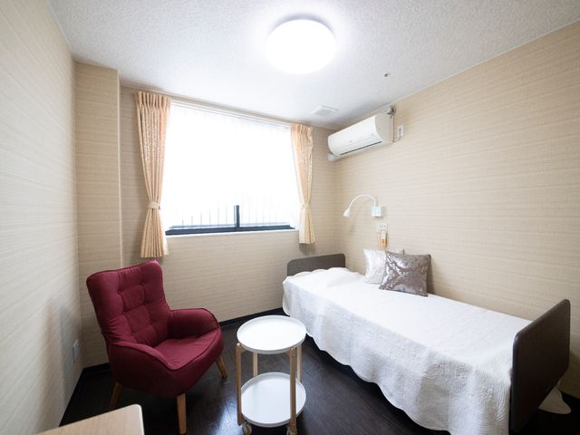 快適な居室空間 居室 温かみのある壁紙と合わせた家具が配された居室です。落ち着いた色合いでゆったりとくつろげる空間が提供されています。