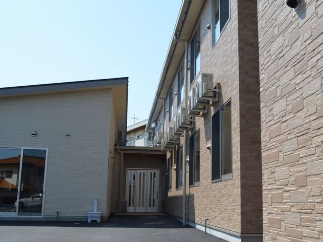 エアコン付き施設外観 外観 広々としたエアコンが設置された建物の入口は、明るく迎え入れるような雰囲気を持っています。快適な環境を求める方に適した外観です。
