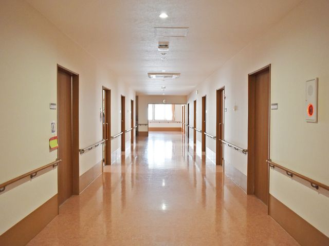 明るい廊下の風景 廊下 広々とした廊下は日当たりが良く、柔らかな光が差し込んで安らぎの空間を演出しています。手すりが整備されており、安心して歩行できる設計になっています。