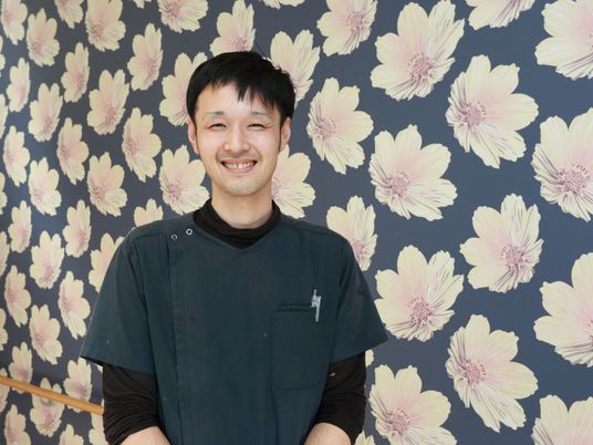 笑顔のスタッフ壁際に立つ