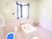 出窓が設置された広々とした浴室である。ピンク色のタイルが床と壁に貼られ、洗い場に青いシャワー椅子が置いてある。