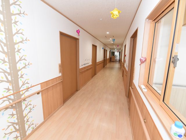 廊下の壁面装飾 通路 温かみのある木目調の壁と床が印象的な廊下です。通路には装飾も施され、居心地の良い空間作りがされています。