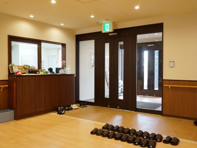 受付とエントランスの様子 玄関 明るく広々としたエントランスは、訪れる方に安らぎを提供します。受付にはスタッフが常駐し、応対にあたっています。