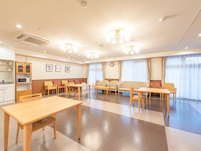 共有スペースの明るい居室 リビング 広々としたダイニングルームは日差しが優しく差し込み、心地良い雰囲気でくつろげる空間です。キッチン併設で、食事の時間も楽しいひとときを提供しています。