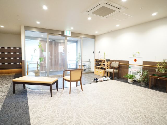 エントランスの検温所 玄関 ゆとりのあるエントランスでは、手指の消毒と体温の確認を行うことができ、衛生面にも配慮がなされています。明るく開放的な雰囲気の中で、ご家族や訪問者の方々をお迎えできます。