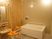 サムネイル 施設の写真 広い洗い場スペースがある浴室。壁には鏡や手すりが設置してあり、ひじ掛けと背もたれがついたシャワーチェアが用意してある。