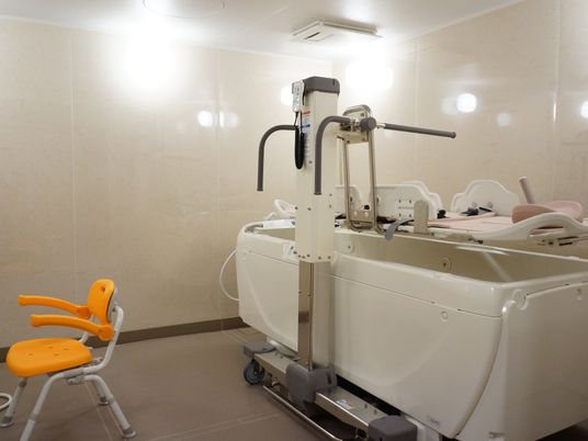施設の写真 寝たまま入浴できる機械が設けてある。要介護度が高い方も無理なく入浴でき清潔が保てる。介護用の椅子が置かれている。