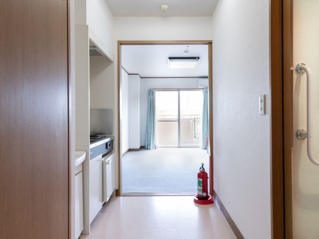 清潔な居室の玄関 居室 明るく開放的なスペースを備えた居室です。安全を考慮し、設置された手すりや消火器も備えております。