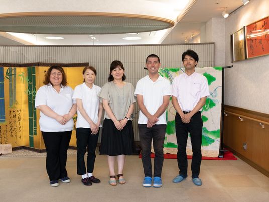 笑顔のスタッフ5人並ぶ廊下