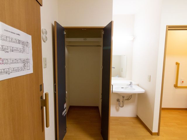 個室の洗面台とドア 居室 広々とした居室の入口には、車椅子でも使いやすい洗面台があり、利用者の快適さを考えた設計です。
