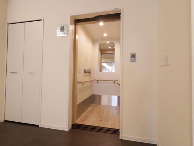 明るい居室の出入口 エレベーター 手すりの付いた居室の入り口は、スタッフと利用者のコミュニケーションも考慮した設計です。ゆとりある空間で働くやりがいを感じられます。