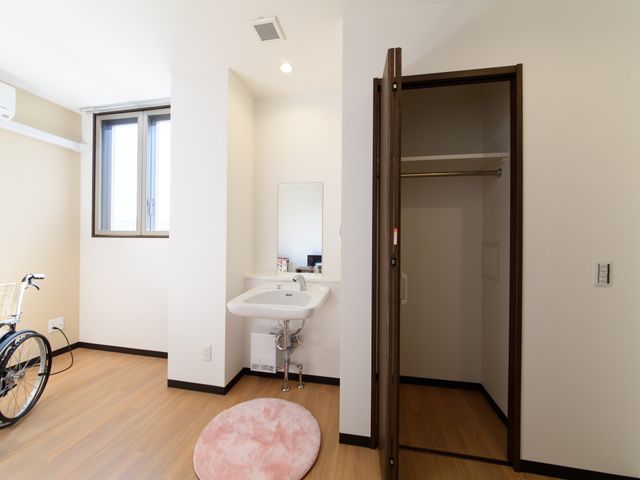 居室内の洗面台とクローゼット 居室 すっきりとした居室で、洗面台の配置もゆったりしており、車椅子を利用される方にも快適です。クローゼットも十分な収納スペースを提供しています。