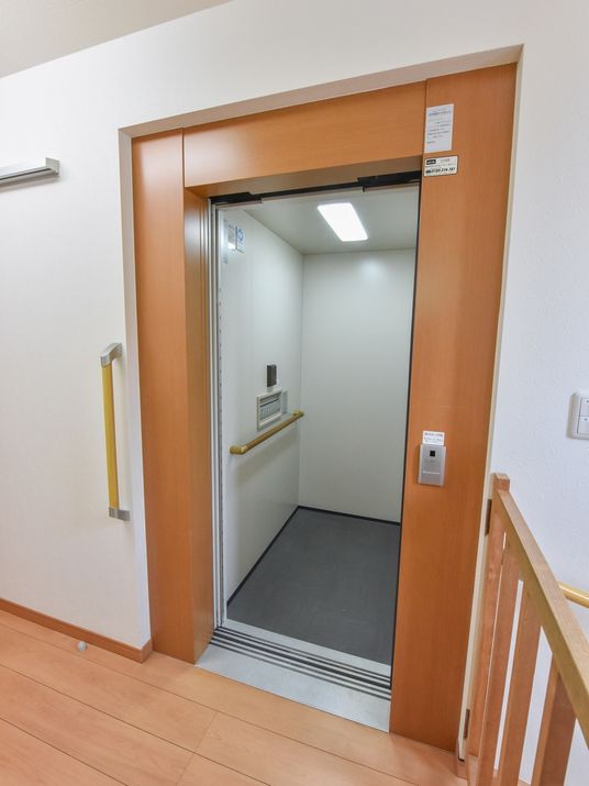 エレベーター内の壁と、入口扉の横に手すりを設置している。エレベーター横にある１階への階段には転落防止の扉がある。
