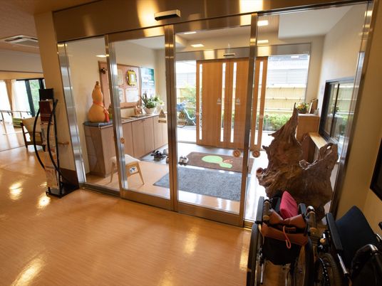 施設の写真 玄関は二重ドアを採用し、館内に入ってすぐ横に縦長のパンフレットラックを置いている。また車椅子なども備えている。
