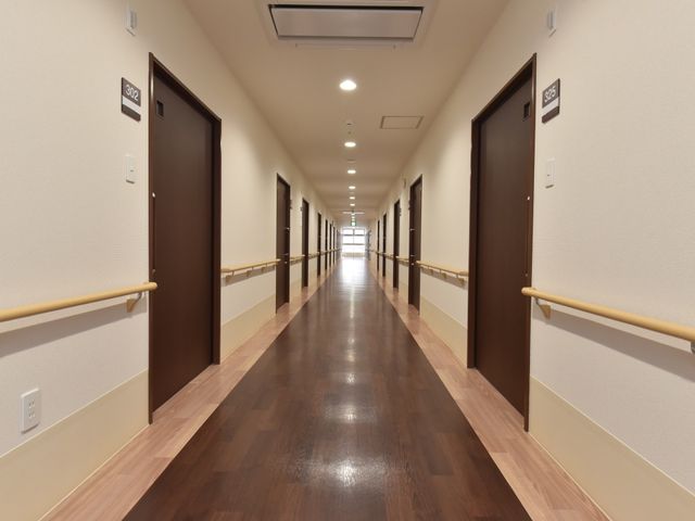 手すり付きの清潔な廊下 廊下 床の反射が美しい廊下は、手すりが設置してあり、安全に移動できる設計です。ここでご利用者様の快適な日々をサポートするお仕事ができます。
