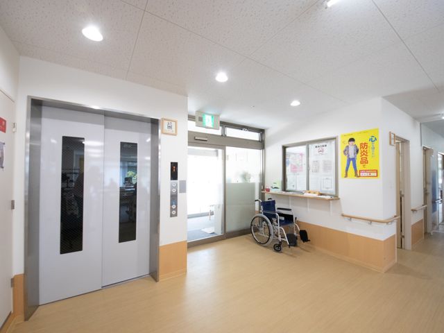 エレベーターと廊下の様子 エレベーター 広々として明るい廊下はわかりやすい案内表示があり、静かな雰囲気です。車椅子が置かれ、誰もが快適に利用できる設計になっています。