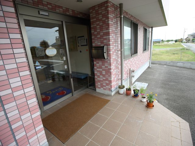 エントランスの明るい風景 玄関 歓迎する雰囲気のエントランスです。温かみを感じる配色と緑の植物が訪れる人々を優しく迎え入れます。