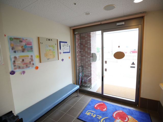 エントランスベンチと掲示物 玄関 きれいに整備されたエントランスです。来訪者を迎える掲示板や待合ベンチが配され、温かい雰囲気を醸し出しています。