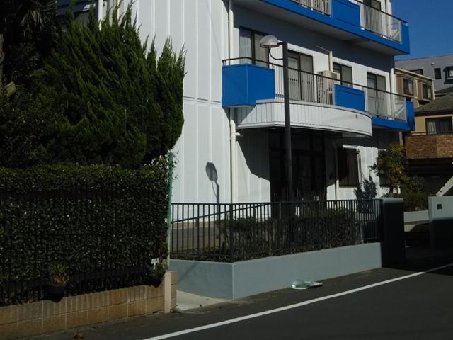 青と白の建物エントランス 外観 朝日が差し込む清潔感のあふれるエントランスです。出入りしやすい広々とした設計で皆様をお迎えします。