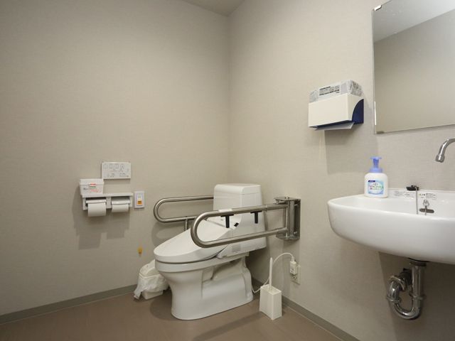 手すり付きトイレ空間 トイレ 清潔感のあるトイレには、手すりや広いスペースが備えられ、利用者の安全と快適さに配慮されています。
