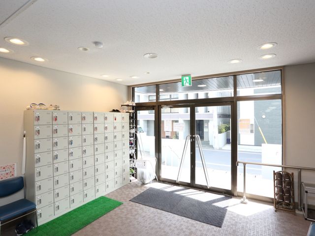 明るいエントランスの一角 玄関 清潔で開放感のあるエントランスは、待合スペースとして利用でき、来訪者を温かく迎え入れます。運動靴等の収納も整然と配され、機能的なスペース設計がされています。