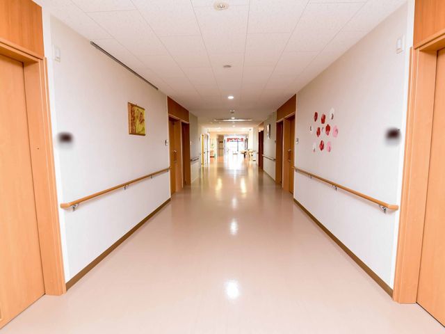 明るい廊下 通路 手すり完備の清潔な廊下は、ゆったりとした歩行を支援します。壁に飾られたアートが温かな雰囲気を演出しています。