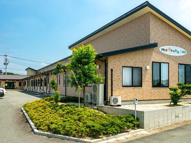 建物外観 外観   落ち着いた色合いの建物と手入れされた植栽が見える外観です。出入口までの通路も確認でき、来訪しやすい印象です。