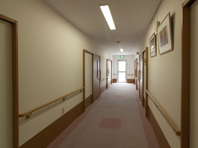 清潔感のある廊下 廊下 手すり付きで清潔な廊下が続いており、壁には絵画が飾られ温かみを感じさせます。利用者の安全と心地よさを考えた設計です。