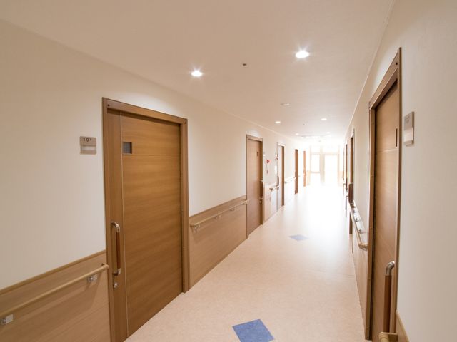 明るい廊下と部屋の扉 通路 ゆったりとした廊下は清潔感に満ちており、部屋の出入りも安全です。ここでの職場環境は整っており、快適にお勤めいただけます。