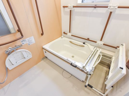 洗い場や浴槽脇に、可動式の台が設置されている。浴槽内の壁の各所にしっかりとした手すりが備わっている。