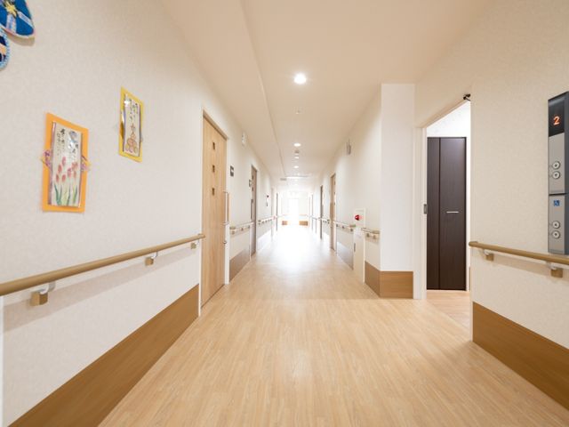 清潔な施設の廊下 通路 手すりが整備された廊下は、暖かみのあるデザインです。安全かつ快適な移動空間を提供しています。