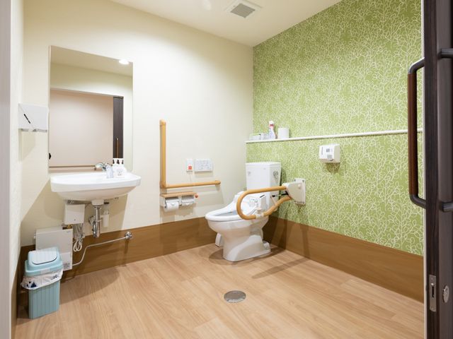 バリアフリー設計のトイレ トイレ 手すり付きで広々とした清潔なトイレ空間。利用者の安全と快適さに配慮した設計がなされています。