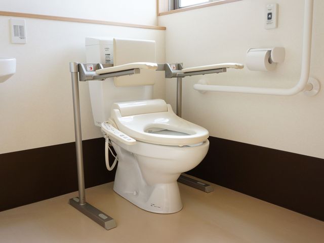 手すり付き清潔なトイレ トイレ 機能的に配慮された手すりで、安心してご利用いただけるトイレです。清掃が行き届いており、衛生的な環境を保っています。