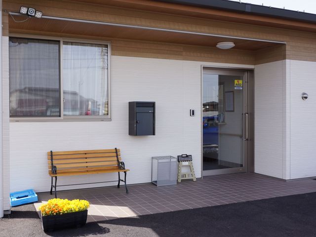 快適なエントランス風景 外観 明るく清潔感のあるエントランスです。ベンチと花でお迎えし、訪れる方々に心地よい空間を提供しています。