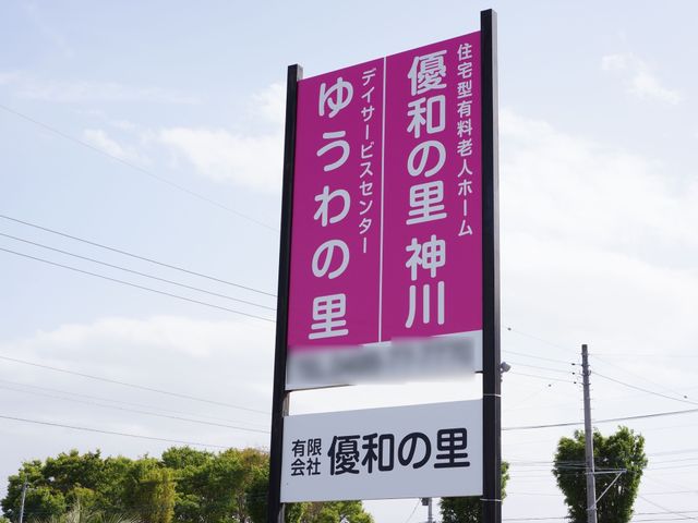 紫色の縦長看板 表示板 目立つ紫色の看板は、通りからも一目で施設の存在が確認でき、訪れる方々の目印になっています。